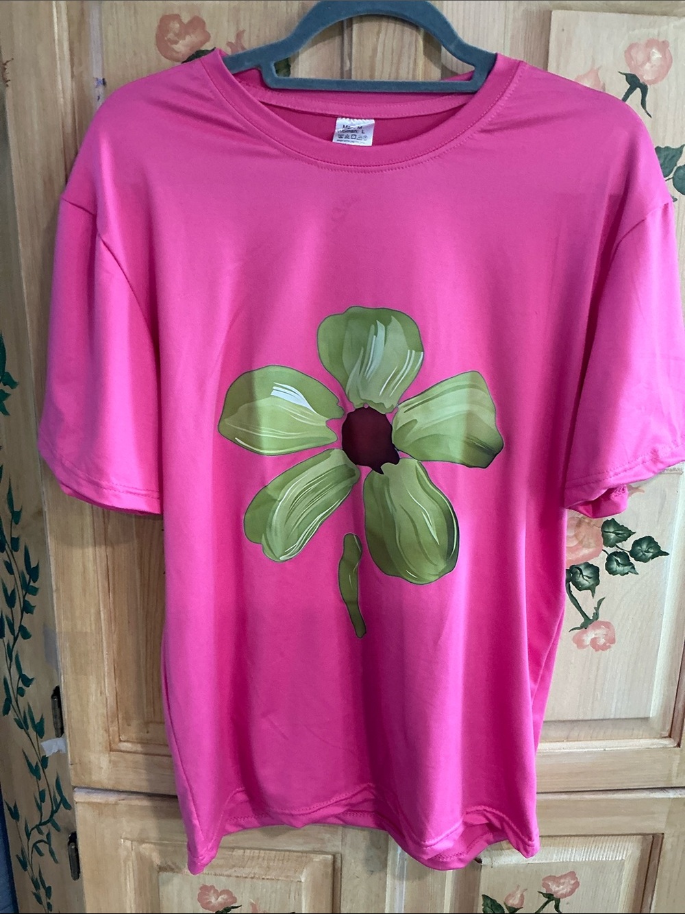 Unisex tshirt in a gorgeous hot pink with a green painted flower in the middle